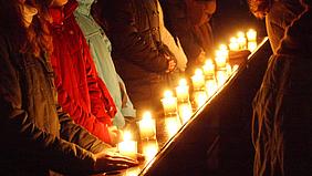 Kerzen auf einer Kirchenbank vor Menschen
