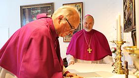 Domkapitular Reinhard Kürzinger unterschreibt sein Dienstversprechen vor Bischof Hanke.